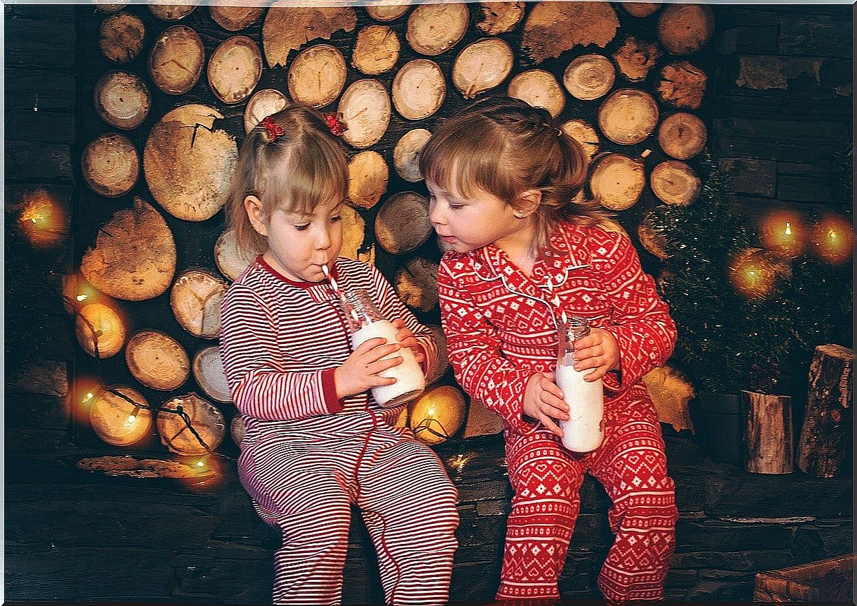 Two girls in pajamas drinking milk during one of the activities to do at home.