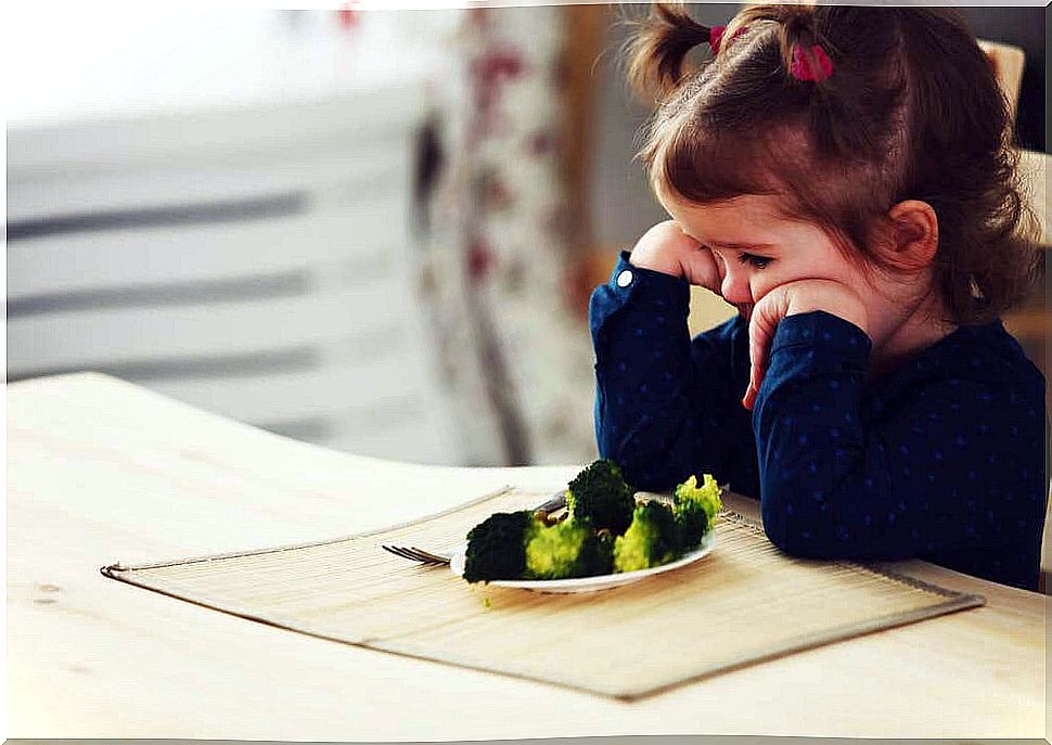 Girl with food neophobia in front of a plate of broccoli 