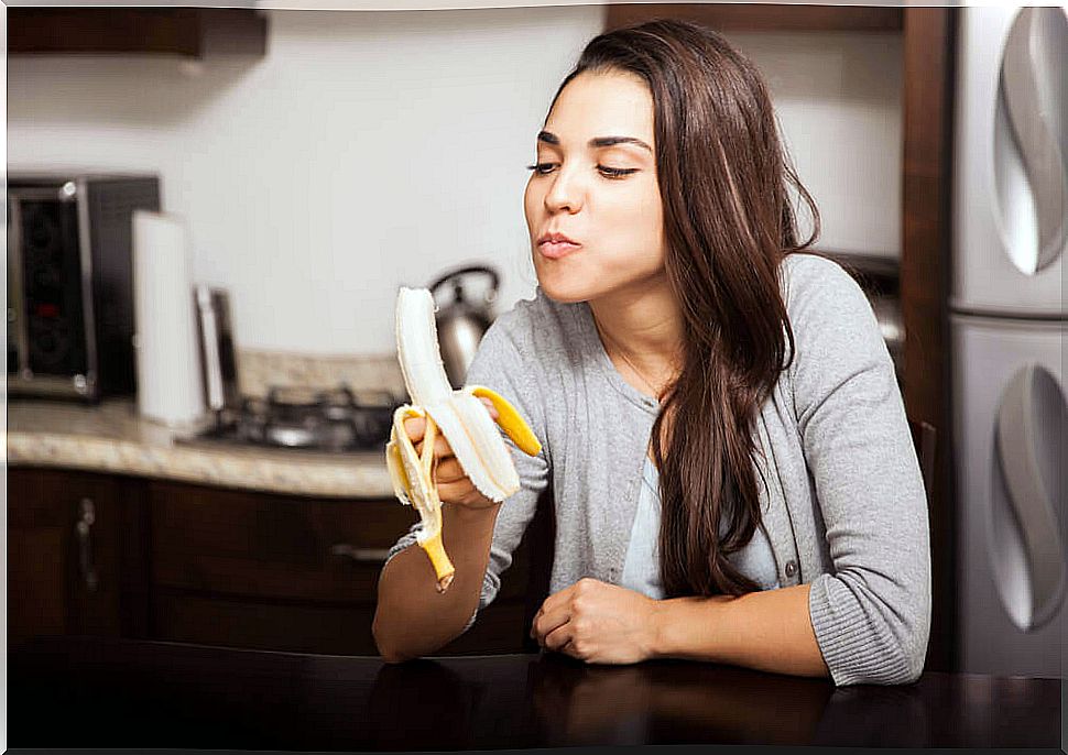 Girl eating a banana, source of carbohydrates.